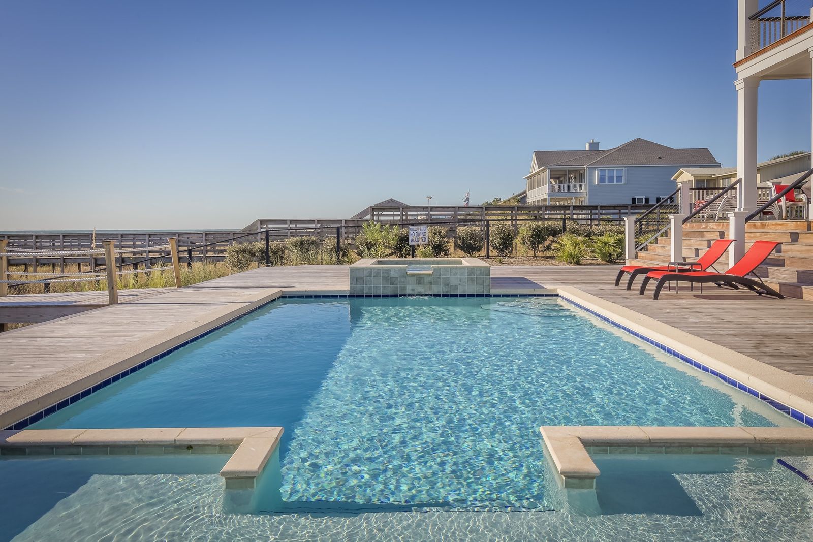 A sparkling-clean backyard pool and spa with a deck and lounge chairs under a clear St. George sky