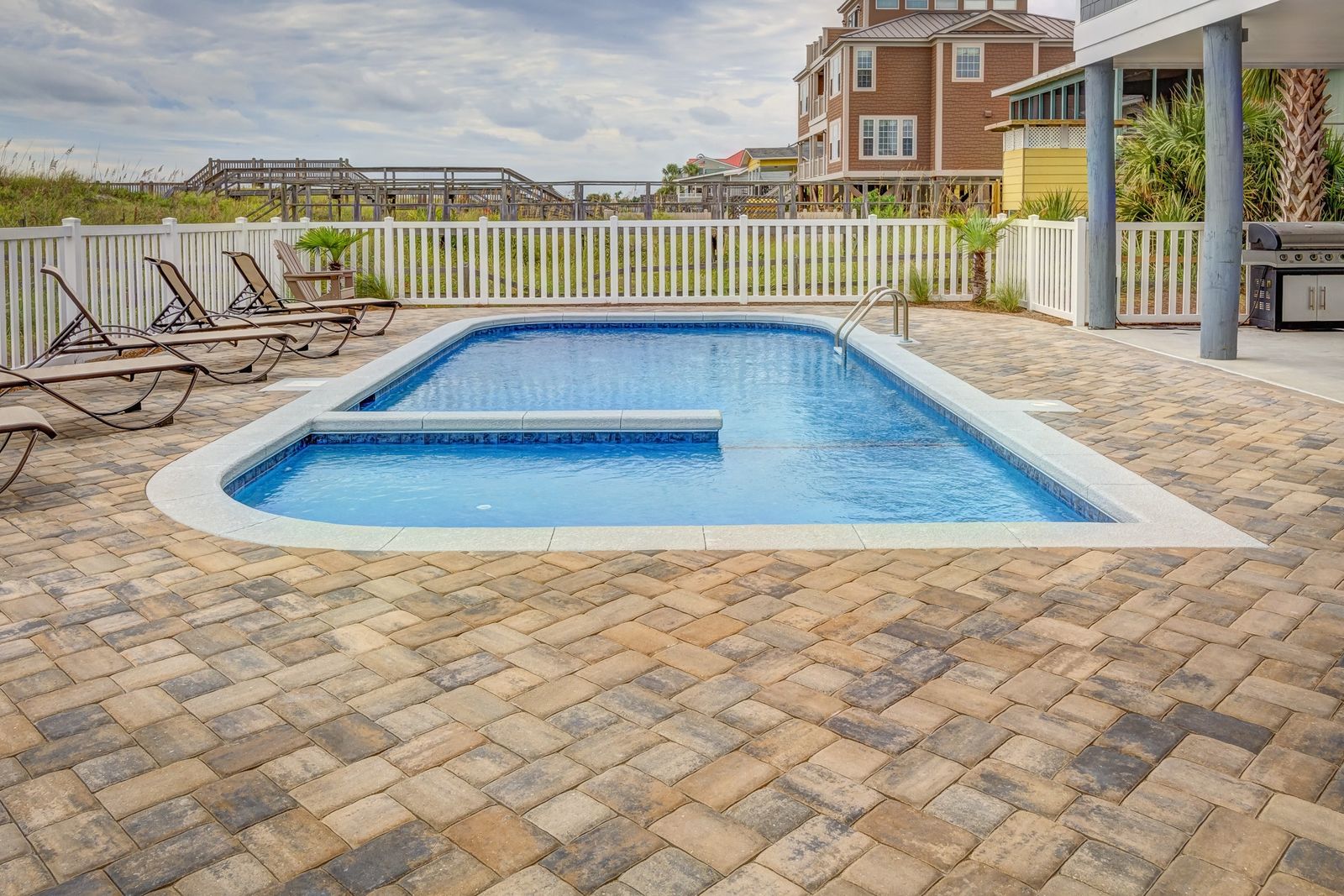 A residential backyard pool and spa with a paver deck and lounge chairs in Southern Utah